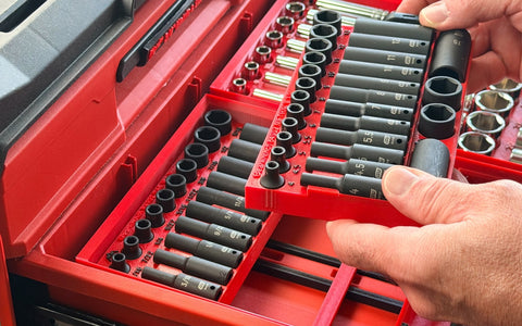 A hand lifting one sub-organizer out of a modular insert while the rest stays in the box